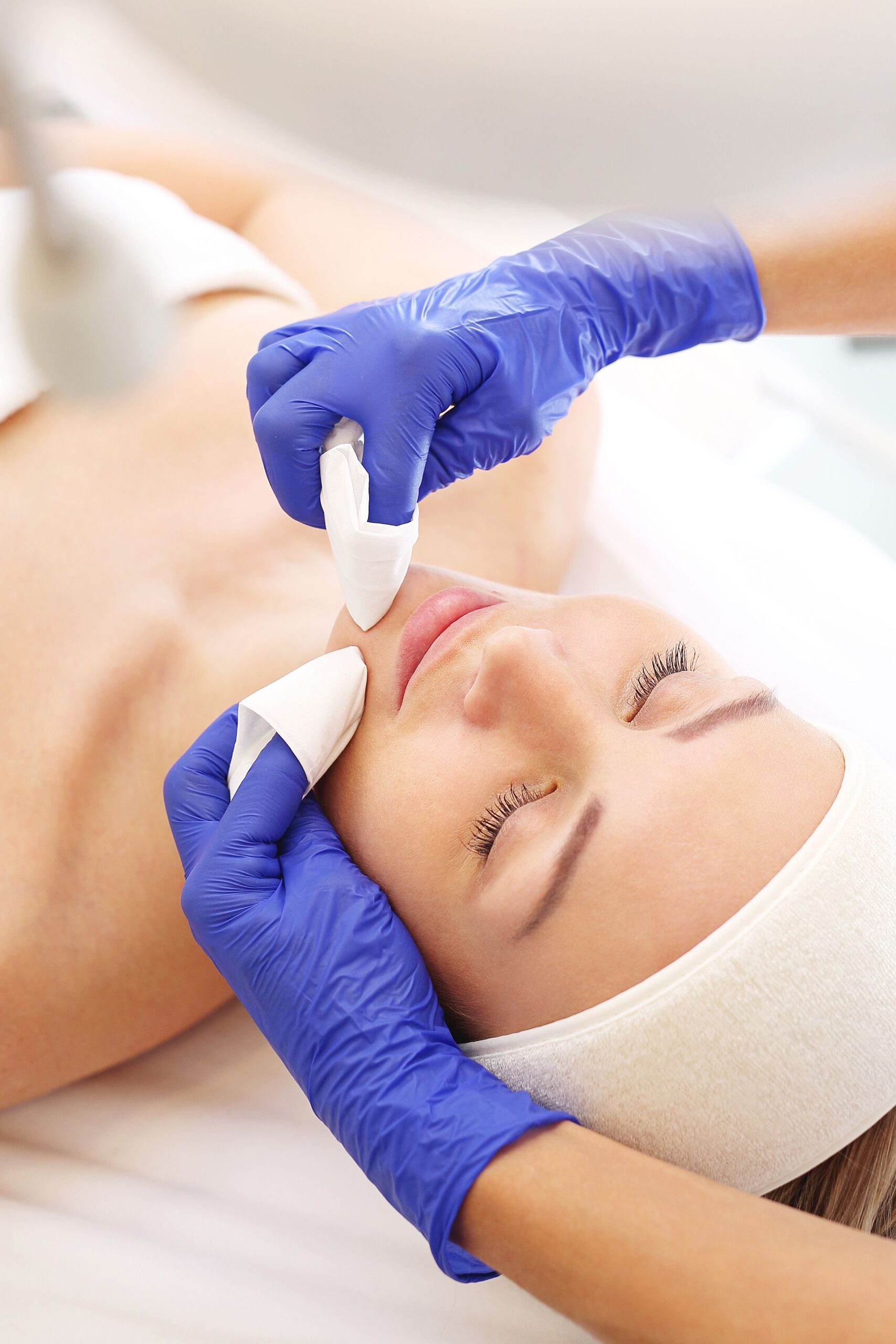 Kosmetyczka oczyszcza skórę kobiety. Oczyszczanie skóry twarzy, kosmetyczka wyciska zaskórniki.