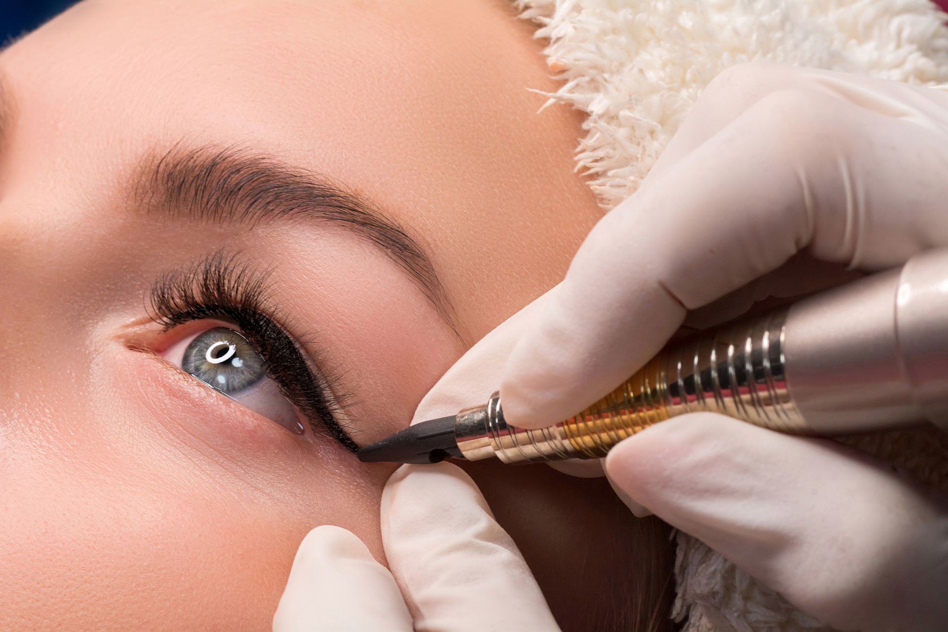Permanent eye makeup close up shot. Cosmetologist applying tattooing of eyes. Makeup eyeliner procedure Permanent eye makeup close up shot. Cosmetologist applying tattooing of eyes. Makeup eyeliner procedure