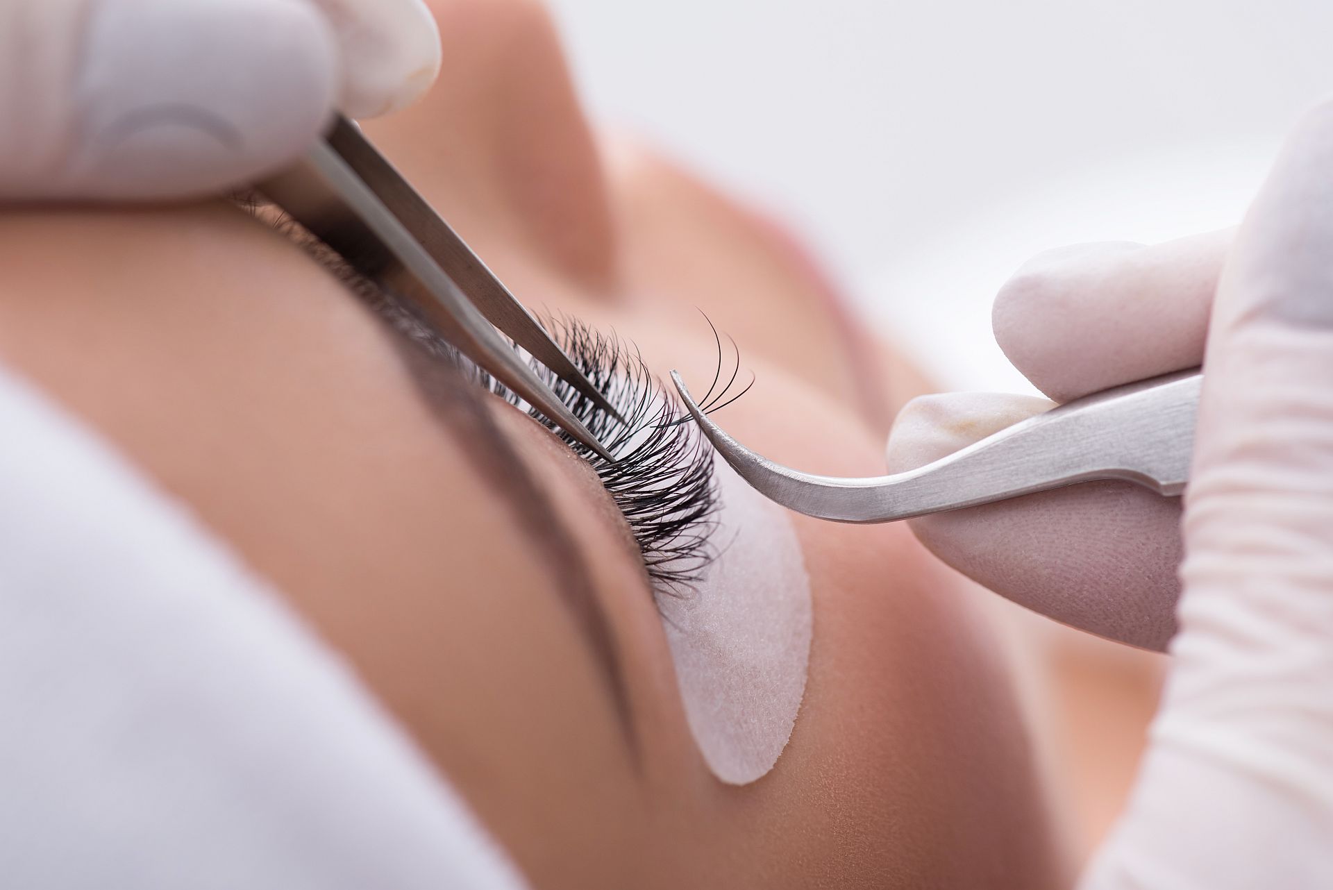 Skillful cosmetologist undergoing lash extension procedure